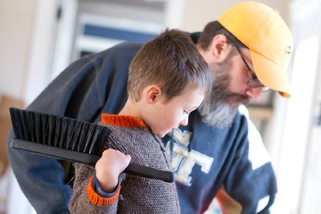 bearded man and boy (wielding a large brush) look down