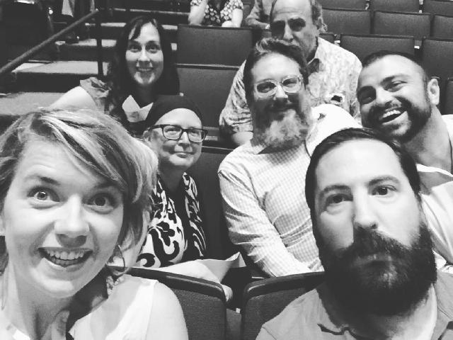 black and white photo of seven people sitting in auditorium seating