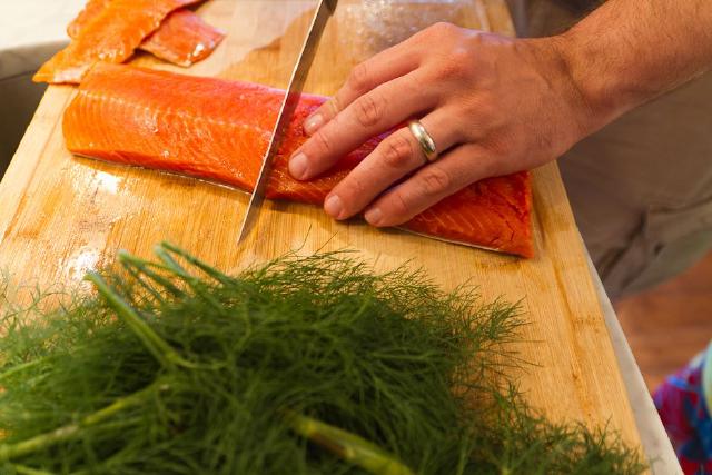 Hands and knife slicing cutting trimmed filet in half