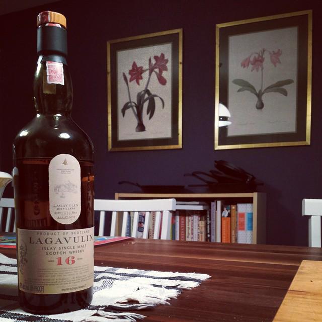bottle of lagavulin scotch whiskey with flower prints on wall in background