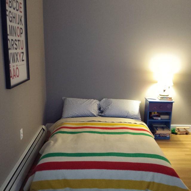 full-size bed with a Hudson Bay blanket on a hardwood floor