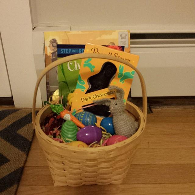 small easter basket holding chocolate rabbit, plastic eggs, and a knitted bunny