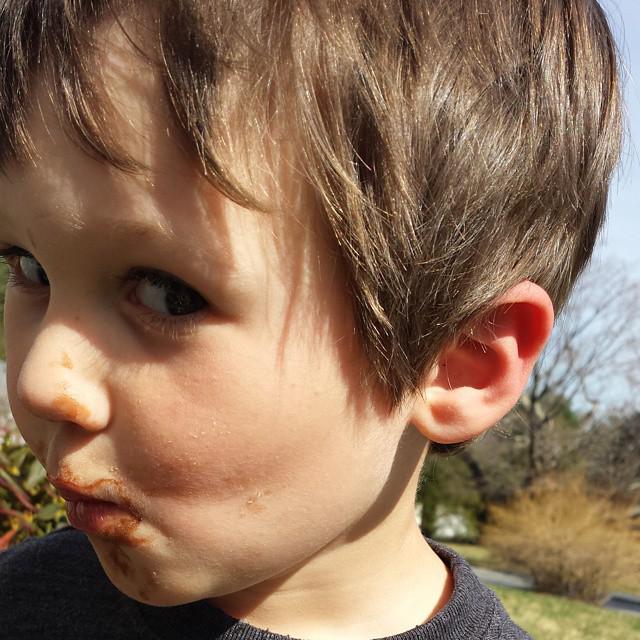 boy with chocolate smeared around his mouth giving a suspicious look