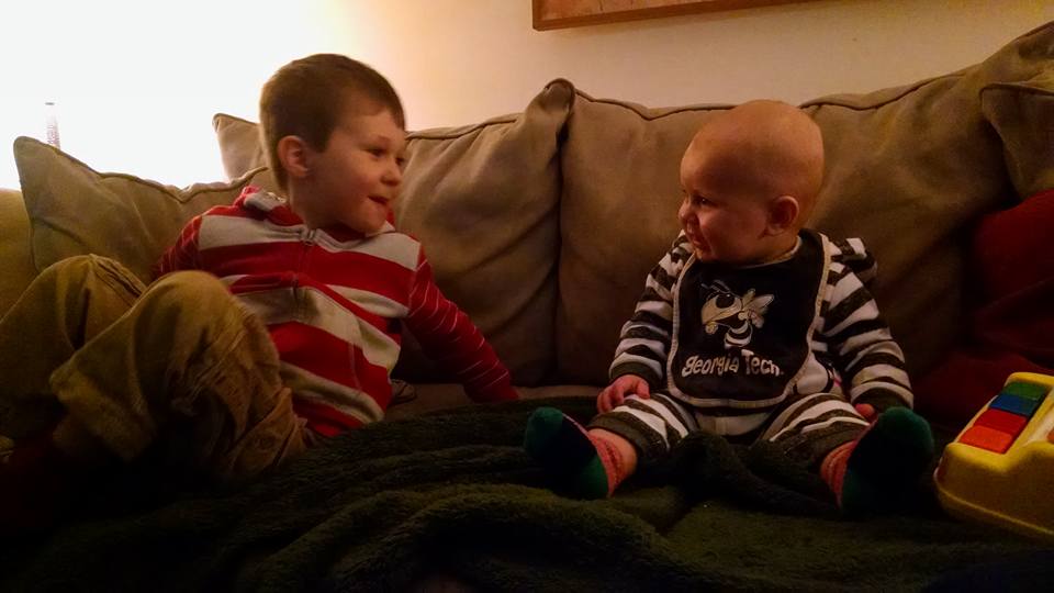 two young boys happily sitting together on couch