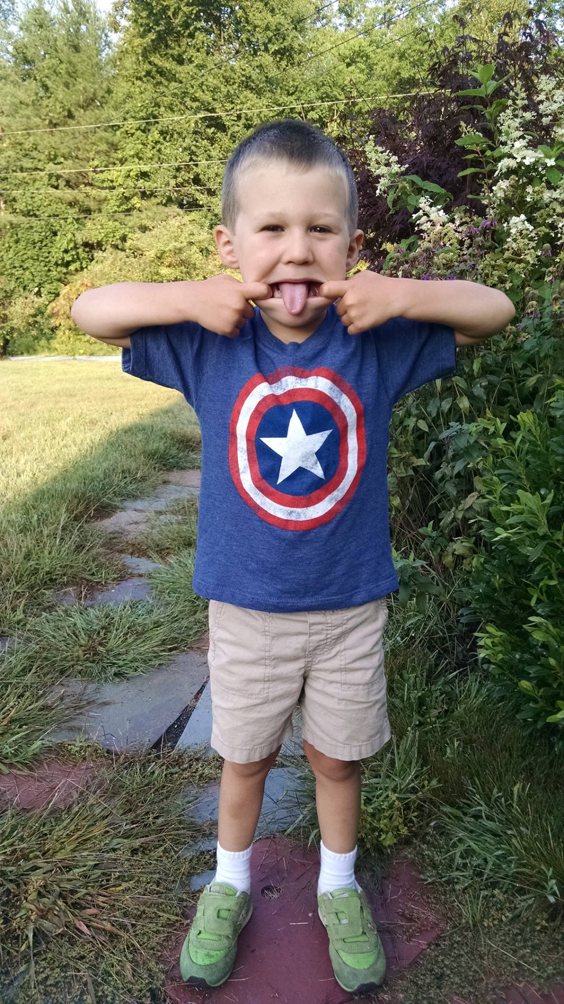 boy in shorts and Captain America t-shirt making a weird face