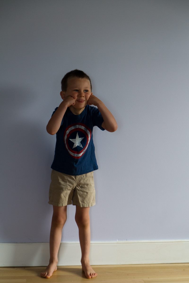 boy in shorts and Captain America t-shirt making a different weird face