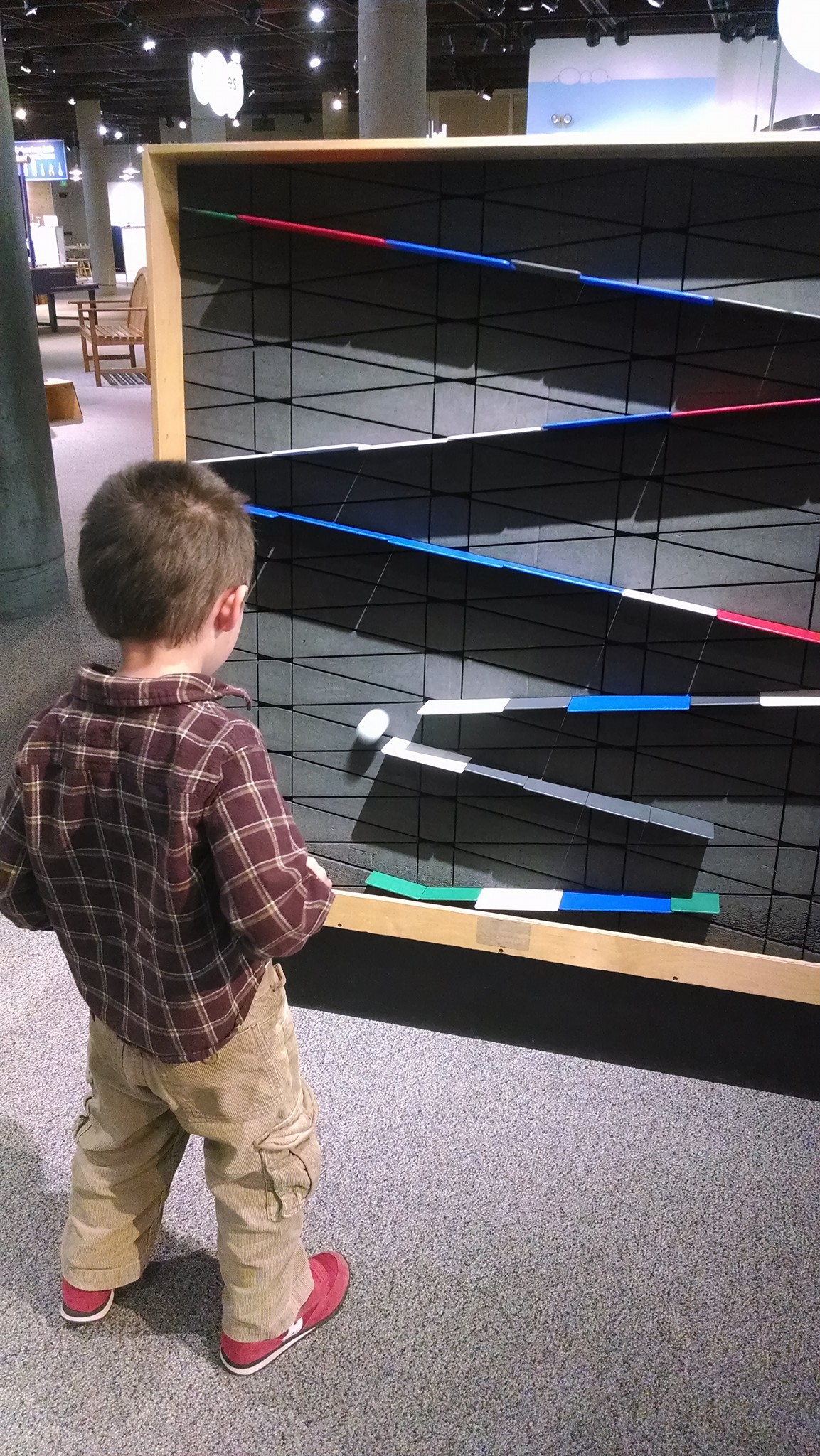 boy looking at ping pong ball falling off plastic ramps