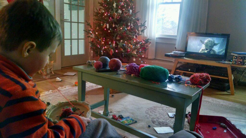 boy sewing with Yoda on the TV next to a Christmas tree