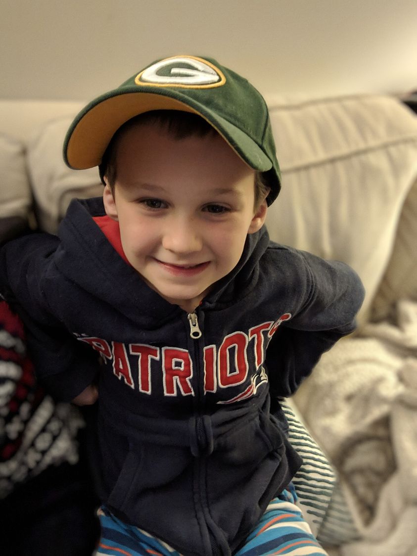 boy wearing a Green Bay Packers hat and New England Patriots sweatshirt